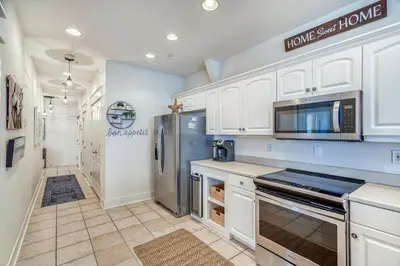 a kitchen with white cabinets and a stainless steel refrigerator at Castle in the Sand by 30A Escapes in Seacrest