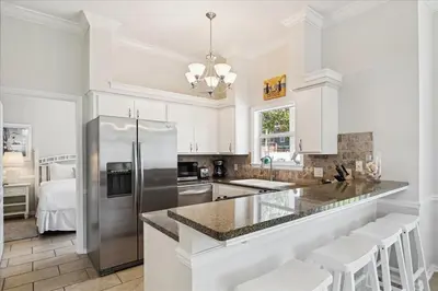 a kitchen with white cabinets and a stainless steel refrigerator at Shiloh by 30A Escapes in Seacrest