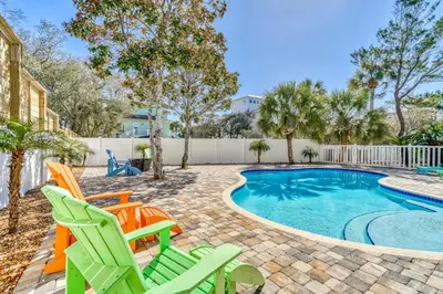 a swimming pool with lawn chairs and a swimming pool at Shiloh by 30A Escapes in Seacrest