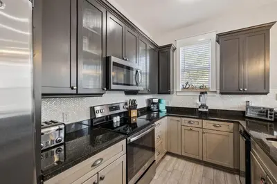 a kitchen with wooden cabinets and black counter tops at Ocean Pearl by 30A Escapes in Rosemary Beach