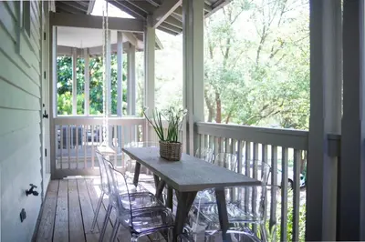a porch with a table and chairs on a deck at Amen Corner by 30A Escapes in Rosemary Beach