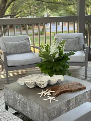 a table with a vase of flowers and two chairs at Amen Corner by 30A Escapes in Rosemary Beach
