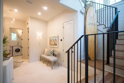a hallway with a staircase with a surfboard on the wall at Amen Corner by 30A Escapes in Rosemary Beach