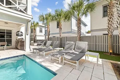 a backyard with a swimming pool and a house with palm trees at High Noon by 30A Escapes in Rosemary Beach