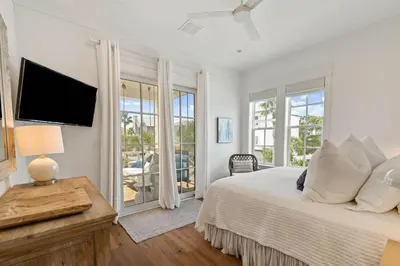 a white bedroom with a bed and a television at High Noon by 30A Escapes in Rosemary Beach