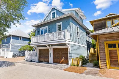 a blue house with a balcony on a street at Sands Cottage Carriage by 30A Escapes in Rosemary Beach