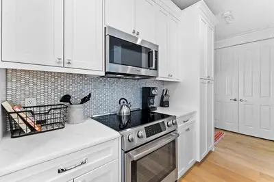 a white kitchen with a stove and a microwave at Sands Cottage Carriage by 30A Escapes in Rosemary Beach