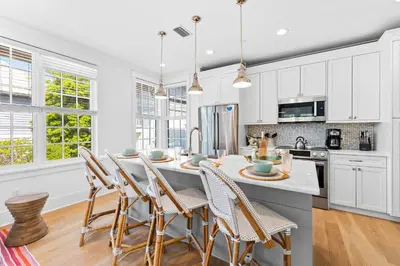 a kitchen with white cabinets and a table with chairs at Sands Cottage Carriage by 30A Escapes in Rosemary Beach