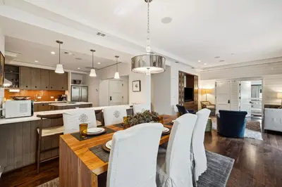 a kitchen and dining room with a wooden table and white chairs at Ocean`s Six by 30A Escapes in Rosemary Beach