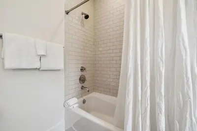 a white bathroom with a tub and a shower curtain at Ocean`s Six by 30A Escapes in Rosemary Beach
