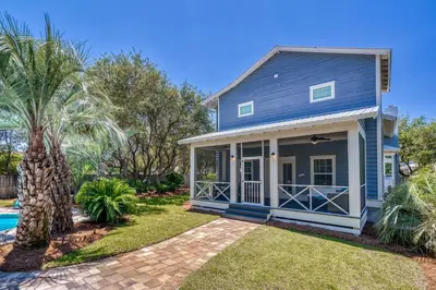 a blue house with a pool and palm trees at All In - Seacrest by 30A Escapes in Seacrest