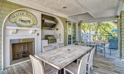 a porch with a wooden table and a fireplace at Moon Landing by 30A Escapes in Watersound Beach
