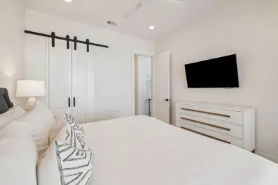 a white bedroom with a bed and a tv at Sea Star by 30A Escapes in Seacrest
