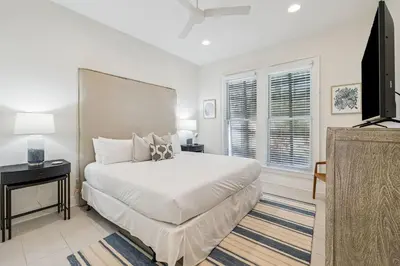 a white bedroom with a bed and a television at Sea Star by 30A Escapes in Seacrest