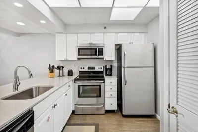 a kitchen with white cabinets and a stainless steel refrigerator at HP 34E On the Gulf by 30A Escapes in Rosemary Beach