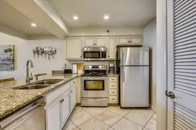 a kitchen with white cabinets and stainless steel appliances at HP 12W Gulf Front Condo by 30A Escapes in Rosemary Beach