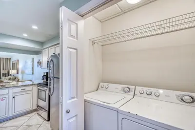 a kitchen with white cabinets and a washer and dryer at HP 12W Gulf Front Condo by 30A Escapes in Rosemary Beach