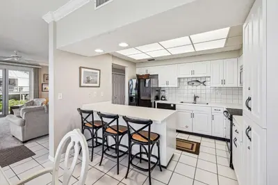 a kitchen with white cabinets and bar stools at HP 16E Beach Treat by 30A Escapes in Rosemary Beach