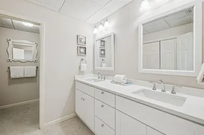 a white bathroom with two sinks and a mirror at HP 16E Beach Treat by 30A Escapes in Rosemary Beach