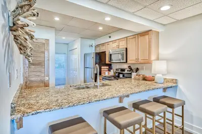 a kitchen with a counter and stools in a room at HP 15W Salt and Light by 30A Escapes in Rosemary Beach