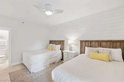 two beds in a bedroom with white walls and yellow pillows at HP 23W Calypso Crossing by 30A Escapes in Rosemary Beach