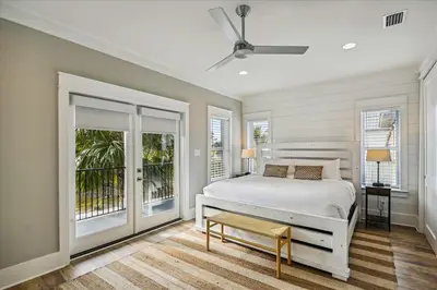 a white bedroom with a bed and a balcony at Makin Memories by 30A Escapes in Rosemary Beach