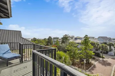 a balcony with a blue chair on a deck at Makin Memories by 30A Escapes in Rosemary Beach