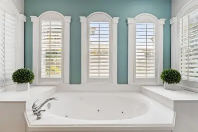 a bathroom with a white tub and three windows at Seagrove Stillhouse by 30A Escapes in Seagrove Beach