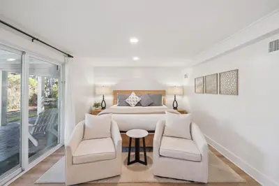 a white bedroom with a bed and two chairs at All Our Summers by 30A Escapes in Seagrove Beach