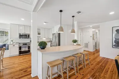 a kitchen with white cabinets and a island with bar stools at All Our Summers by 30A Escapes in Seagrove Beach