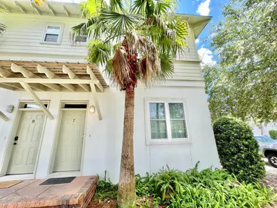 a palm tree in front of a white house at Sunnyside #7 by 30A Escapes in Seacrest