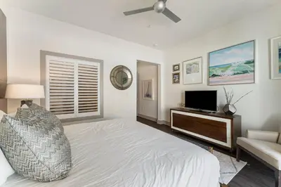a white bedroom with a bed and a television at The Pointe Unit 111 by 30A Escapes in Rosemary Beach