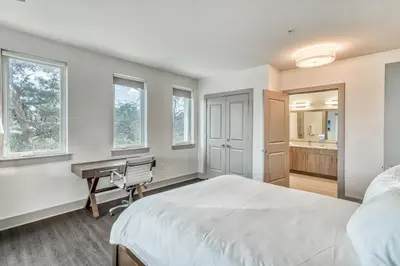 a bedroom with a bed and a desk and windows at The Pointe Unit 121 by 30A Escapes in Rosemary Beach