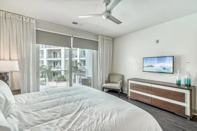 a white bedroom with a bed and a tv at The Pointe Unit 121 by 30A Escapes in Rosemary Beach