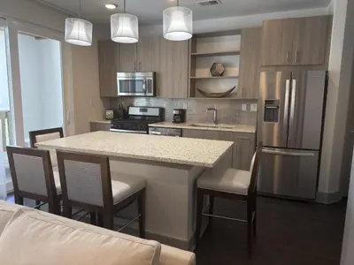a kitchen with a kitchen island with chairs and a refrigerator at The Pointe Unit 122 by 30A Escapes in Rosemary Beach