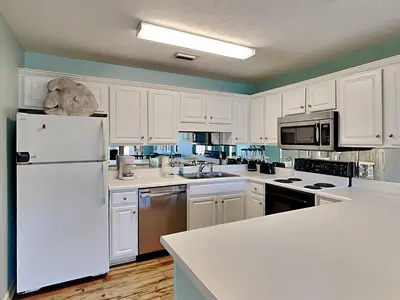 a kitchen with white cabinets and a white refrigerator at Horizon South 57-105 in Panama City Beach