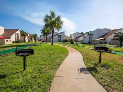 a walkway in a park with palm trees and houses at Horizon South 57-105 in Panama City Beach