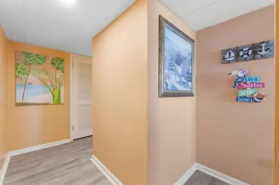 a living room with orange walls and a hallway at Moondrifter 207 in Panama City Beach