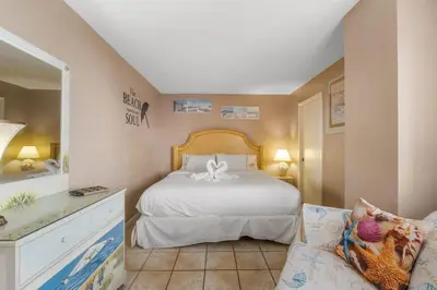 a bedroom with a white bed and a couch at Moondrifter 207 in Panama City Beach