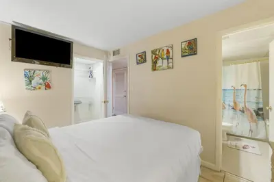 a bedroom with a white bed and a flat screen tv at Moondrifter 207 in Panama City Beach