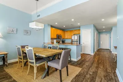 a kitchen and dining room with a wooden table and chairs at Stunning Gulf Front 3BD Condo! with Beach Chair Service for 4! presented by Dolce Vita Getaways PCB! in Panama City Beach