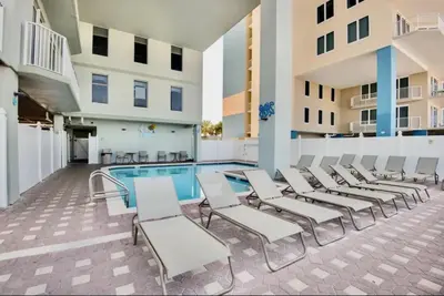 a pool with chaise lounge chairs next to a building at Stunning Gulf Front 3BD Condo! with Beach Chair Service for 4! presented by Dolce Vita Getaways PCB! in Panama City Beach