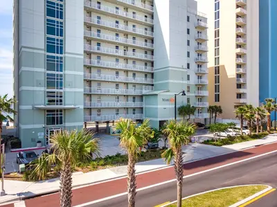 a street with palm trees in front of a tall building at Stunning Gulf Front 3BD Condo! with Beach Chair Service for 4! presented by Dolce Vita Getaways PCB! in Panama City Beach