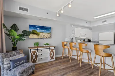 a kitchen and living room with a bar and stools at Shores of Panama 1408 - Seaside Getaway in Panama City Beach