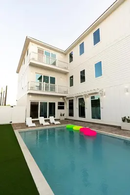 a house with a swimming pool in front of a building at The Taj Of The Gulf! Luxury Beach Mansion! Sleeps 37, private pool & hot tub, putting golf in Panama City Beach