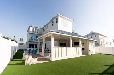 a white house with a yard with green grass at The Taj Of The Gulf! Luxury Beach Mansion! Sleeps 37, private pool & hot tub, putting golf in Panama City Beach