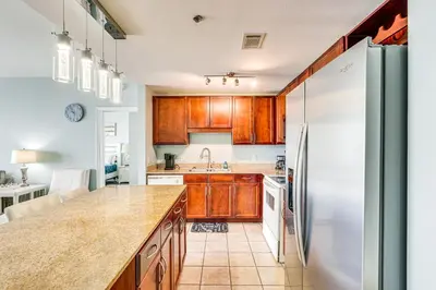 a kitchen with wooden cabinets and a stainless steel refrigerator at Panama City Beach Condo - Walk to the Ocean! in Panama City Beach
