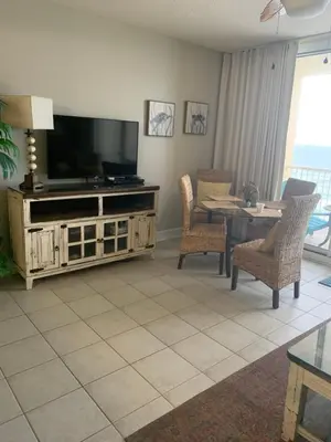 a living room with a television and a table and chairs at Majestic Beach Towers 905 in Panama City Beach