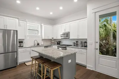 a kitchen with white cabinets and a island with bar stools at Special ! Free Golf Cart ! Spring Paradise! in Panama City Beach
