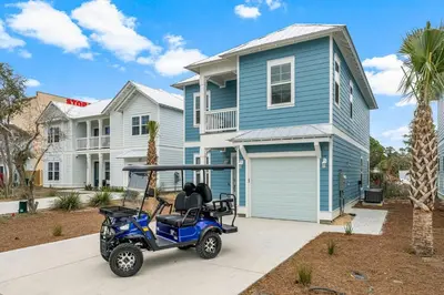 a golf cart parked in front of a blue house at Special ! Free Golf Cart ! Spring Paradise! in Panama City Beach